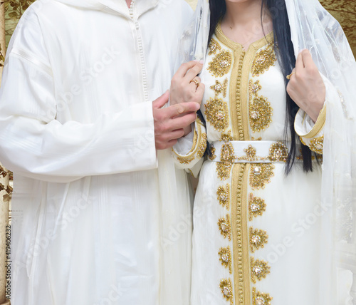 The traditional Moroccan caftan. A bride wearing a caftan next to her husband, who wears a Moroccan jellaba