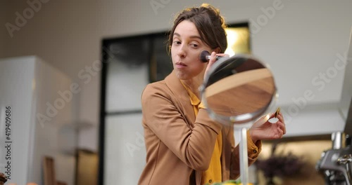 Fussy young businesswoman in a hurry to work in the morning, drinking coffee, chatting on phone and apllying makeup on the go photo