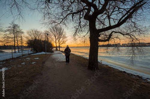 Dawn in the spring by the sea..A man walks along the alley on the embankment in Helsinki, Finland