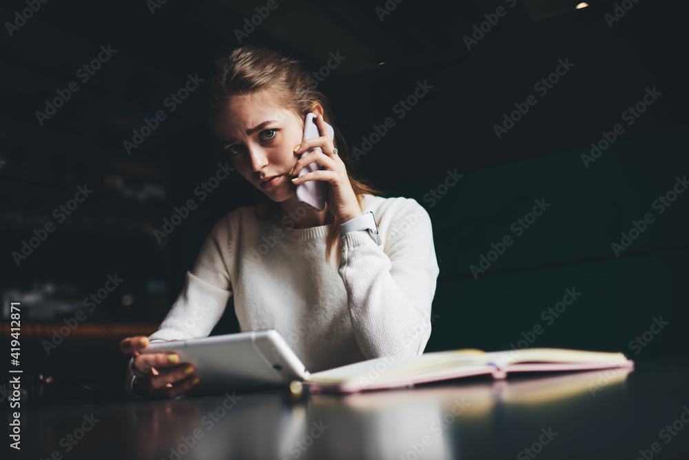 Upset woman talking on smartphone and browsing tablet Upset woman talking on smartphone and browsing tablet
