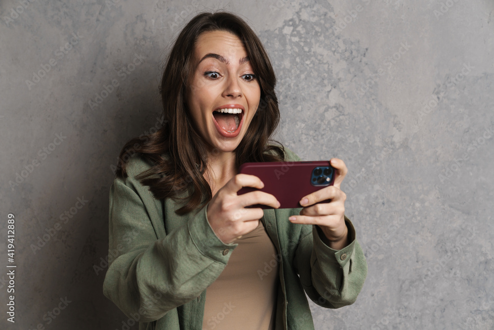 Fototapeta premium Delighted charming girl playing online game on mobile phone