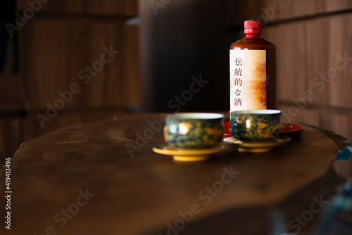 Two oriental cups with a bottle of alcoholic drink in the background