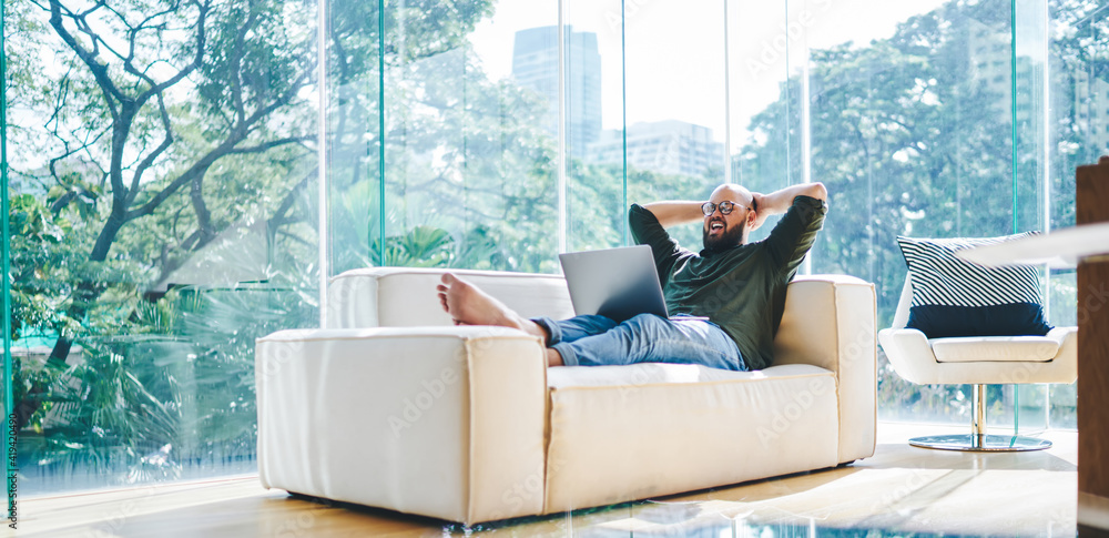 Ταπετσαρία Happy man browsing laptop in modern conservatory