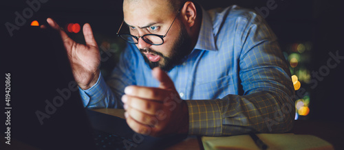 Fotografie Puzzled man looking at screen of laptop