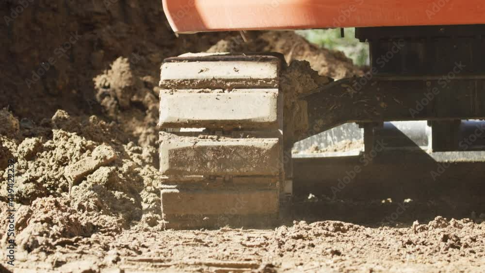 A low angle of a small backhoe digging a drainage ditch. Earth moving equipment A low angle of a small backhoe digging a drainage ditch. Earth moving equipment