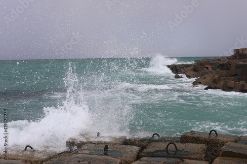 Waves breaking on rocks. Scenic landscape on a cold rainy day. View of big wave crashing on rock. Natural seascape background.