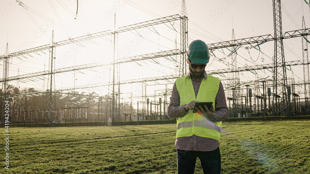Electrical engineer wearing a helmet and safety vest working with