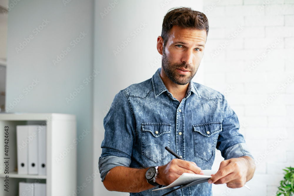 Handsome businessman sitting on a desk, writing notes. Businessman making businessplan.. Handsome businessman sitting on a desk, writing notes. Businessman making businessplan..