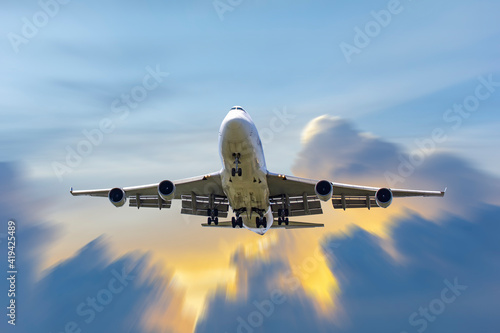 front image commercial passenger aircraft or cargo transportation airplane fly to sky with sunshine and cloudy (background effect motion blur)