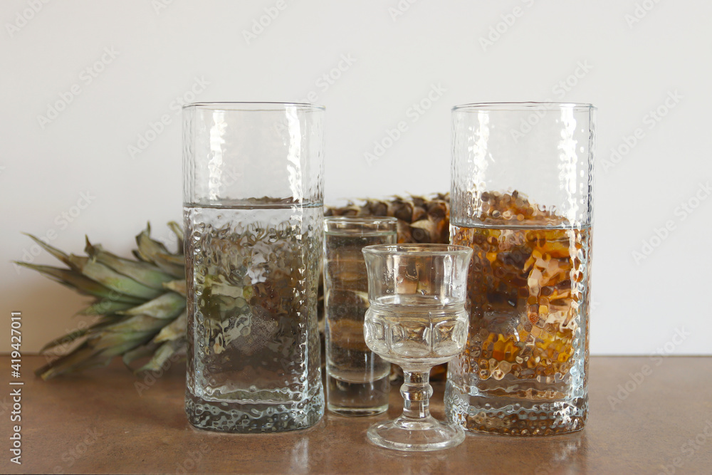 Pineapple behind the glass of water. Reflection of pineapple in a glass of water. Abstract food background. Pineapple behind the glass of water. Reflection of pineapple in a glass of water. Abstract food background.