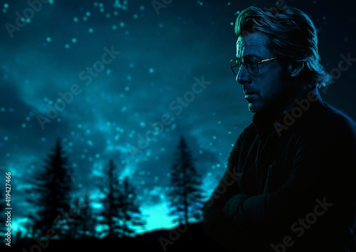 Man with eyeglasses outdoors near fir forest under a starry sky at night. Side view.