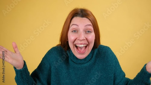 Fun beautiful red hair young woman posing isolated on yellow background studio. People sincere emotions lifestyle concept. Looking at camera charming smile scream happy rejoices winner