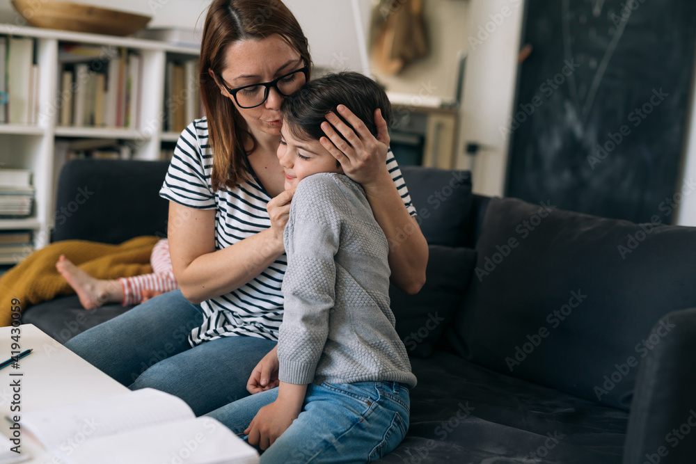 mother helping her son to do homework. she is kissing him mother helping her son to do homework. she is kissing him