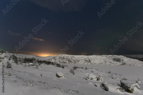 Aurora and stars in the sky .The rocks and ground are covered with snow.Arctic.