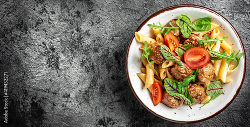 Penne pasta with meatballs in tomato sauce and vegetables in bowl. Italian pasta. Long banner format, top view