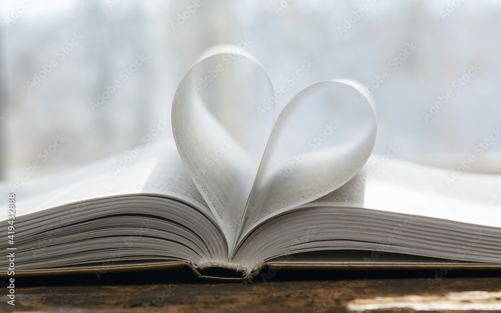 An open book. The pages are folded in the shape of a heart. Blurred background. Concept-romance, Valentine's Day An open book. The pages are folded in the shape of a heart. Blurred background. Concept-romance, Valentine's Day