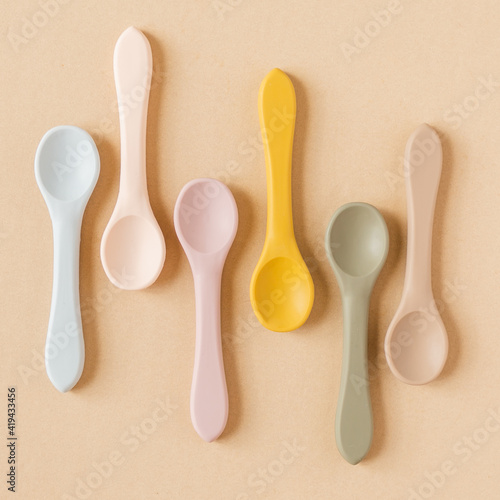 Silicone baby spoons on tan background photo