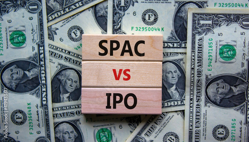 SPAC vs IPO symbol. Blocks with words 'SPAC, special purpose acquisition company' and 'IPO, initial public offering' on background from dollar bills, copy space. Business and SPAC vs IPO concept.