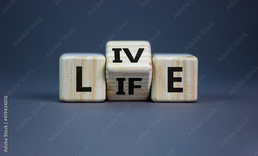 Live your life symbol. Turned cubes and changed the word 'live' to 'life'. Beautiful grey background, copy space. Business, live your life concept. Live your life symbol. Turned cubes and changed the word 'live' to 'life'. Beautiful grey background, copy space. Business, live your life concept.