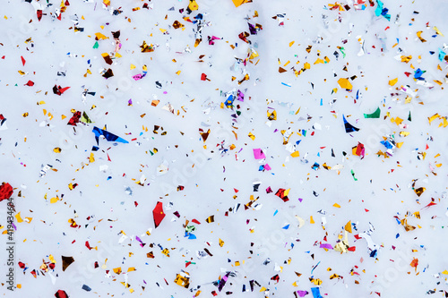 Colorful Confetti on white snow background, close-up.