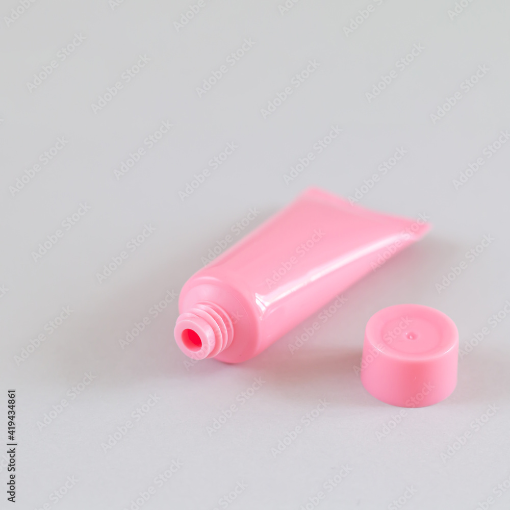 Pink open cosmetic tube on gray background Pink open cosmetic tube on gray background