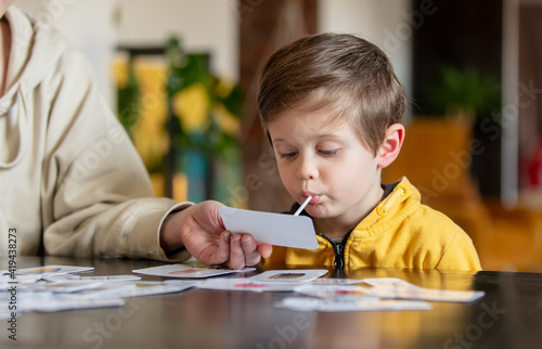 little boy learns words from cards under the ABA therapy program at home at the table