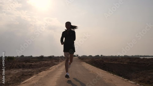 The silhouette of a girl jogging in the evening photo