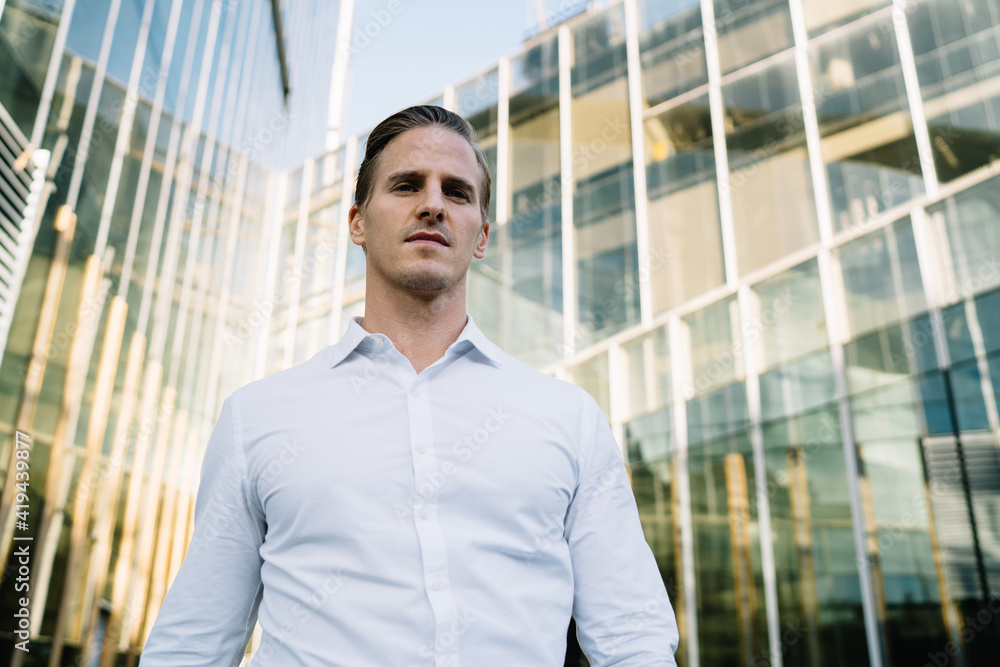 Confident businessman in formal shirt standing outside modern building Confident businessman in formal shirt standing outside modern building