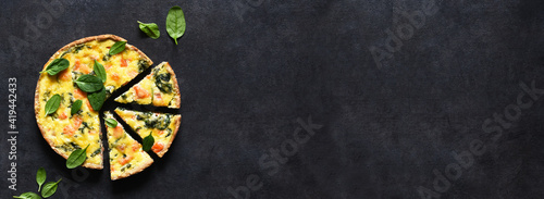 Tart with salmon and spinach, cheese on a black concrete background. Quiche with fish. © zefirchik06