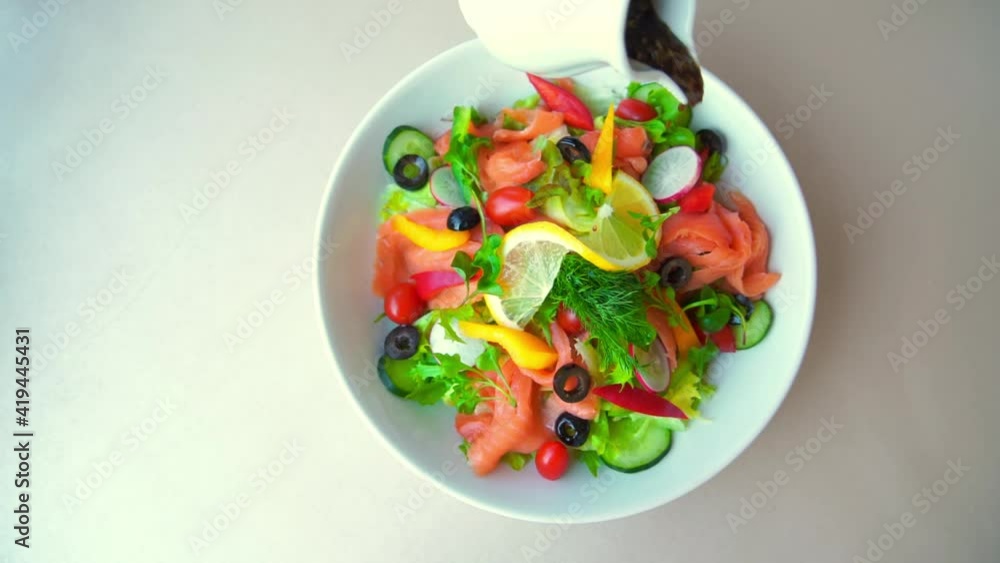 The dressing is sloping onto the smoked salmon salad. Which is beautifully arranged in a plate and ready to be served The dressing is sloping onto the smoked salmon salad. Which is beautifully arranged in a plate and ready to be served