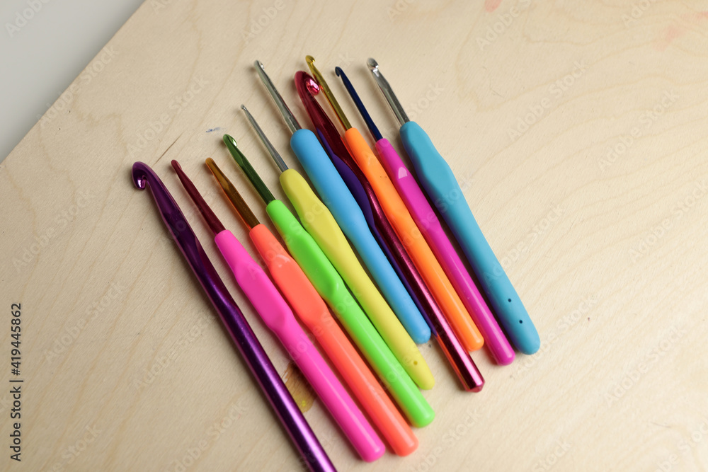 colored crochet hooks on wooden background colored crochet hooks on wooden background