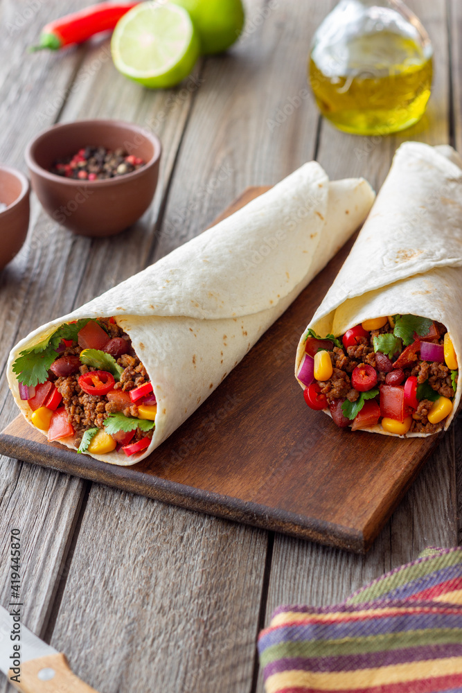 Burritos with meat, beans, corn, tomatoes, onions and chilli. Mexican food. Recipe.