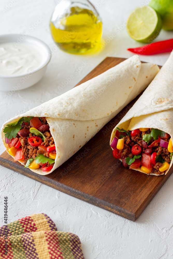 Burritos with meat, beans, corn, tomatoes, onions and chilli. Mexican food. Recipe.