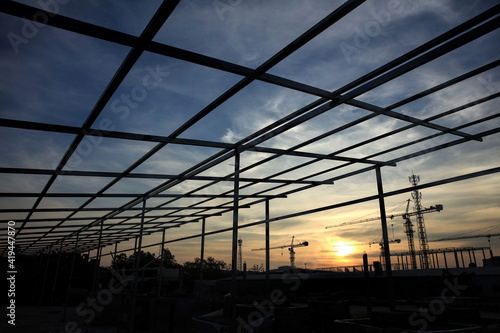 Silhouette steel frame of new factory structure aginst sun set during twiligh time