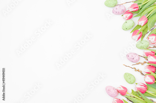 Flat lay easter composition with pink tulips and eggs on white background