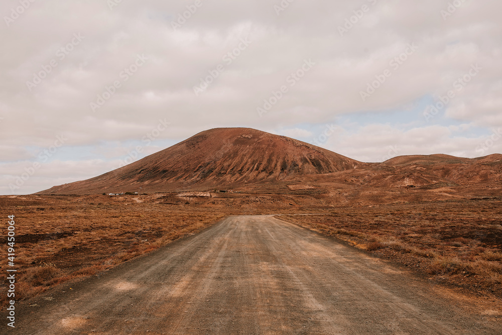 Picturesque view of empty roadway running through dry terrain towards mountain on Lanzarote Picturesque view of empty roadway running through dry terrain towards mountain on Lanzarote