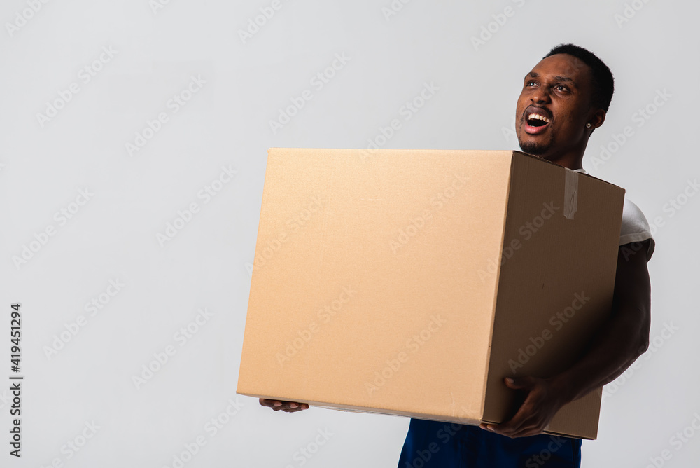 Delivery man holding a white T-shirt and blue pants with a box in his hands. Isolated on a white background. Concept of delivery, mail, shipment, loader, courier. Box close up Delivery man holding a white T-shirt and blue pants with a box in his hands. Isolated on a white background. Concept of delivery, mail, shipment, loader, courier. Box close up