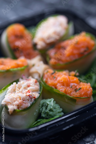 set of sushi rolls with seafood on a black stone background