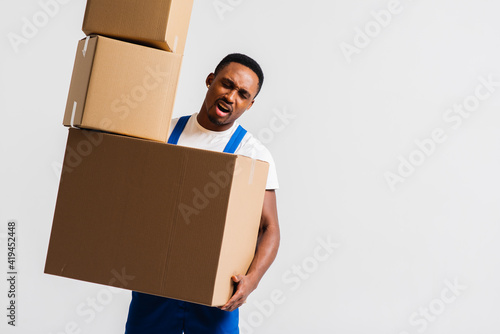 A delivery man wearing a white T-shirt and blue pants holds boxes in his hands. Isolated on a white background. Concept of delivery, mail, shipment, loader, courier. Box close up. Sign language