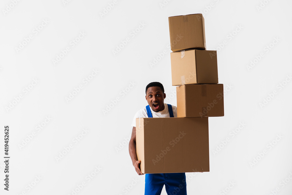 A delivery man wearing a white T-shirt and blue pants holds boxes in his hands. Isolated on a white background. Concept of delivery, mail, shipment, loader, courier. Box close up. Sign language A delivery man wearing a white T-shirt and blue pants holds boxes in his hands. Isolated on a white background. Concept of delivery, mail, shipment, loader, courier. Box close up. Sign language