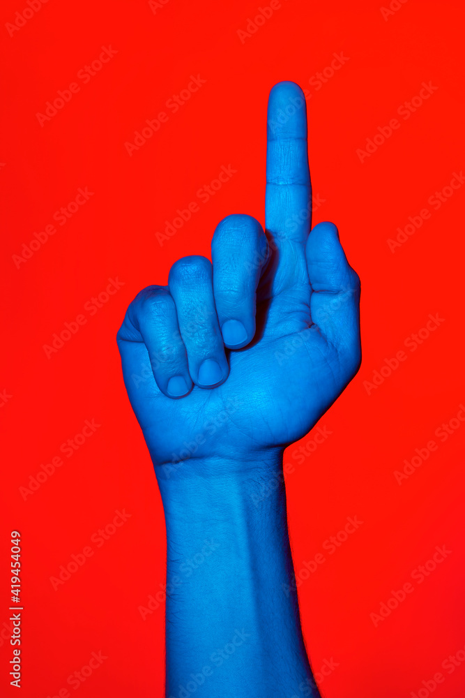 Man's blue hand making the number one sign over red background. Isolated  vertical photo Stock Photo