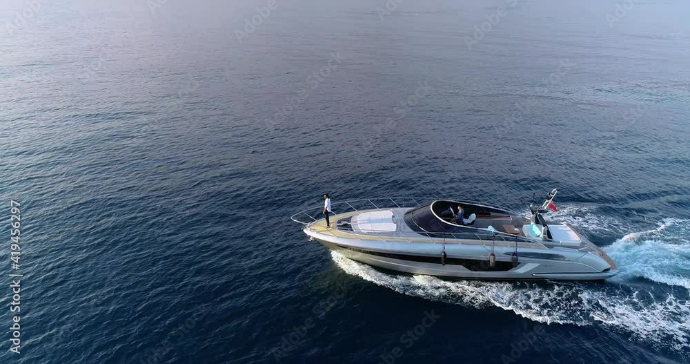 Yacht sailing in the Mediterranean Sea, with a man standing in front of the boat. View from the side Yacht sailing in the Mediterranean Sea, with a man standing in front of the boat. View from the side