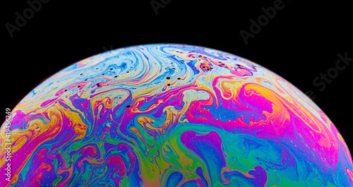 Panoramic view of closeup bubble textured backdrop representing colorful planet with wavy lines on round shaped surface on black background photo