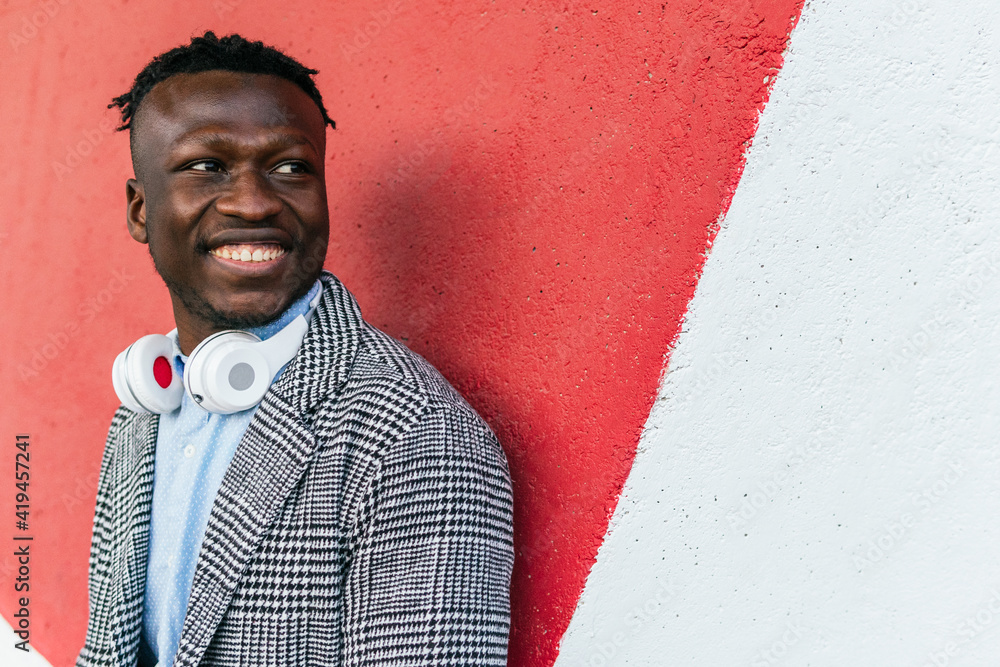 © David Munoz/ADDICTIVE STOCK - Young positive black male manager in formal clothes with modern wireless headset looking away near bright wall in town © David Munoz/ADDICTIVE STOCK - Young positive black male manager in formal clothes with modern wireless headset looking away near bright wall in town