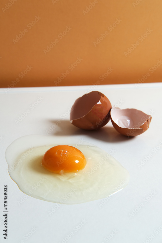 From above of fresh raw chicken egg placed on white background in bright studio From above of fresh raw chicken egg placed on white background in bright studio