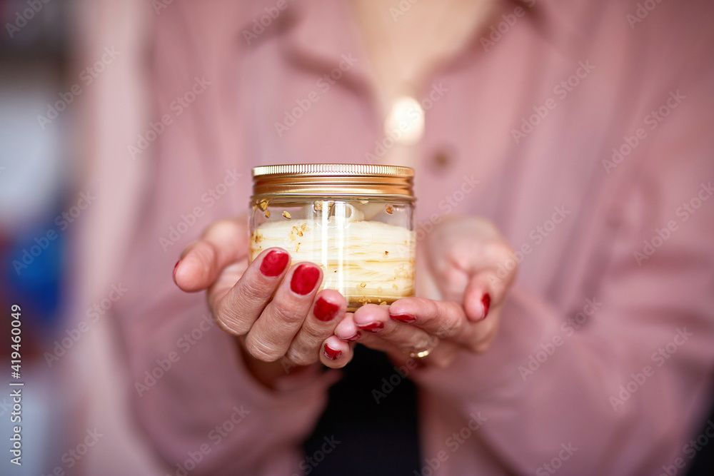 Woman is holding a beige natural cream with red manicure, close up. Copy space. Beauty concept Woman is holding a beige natural cream with red manicure, close up. Copy space. Beauty concept