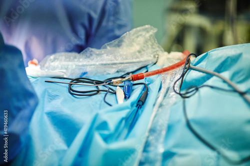 Crop unrecognizable doctors standing near operating table with blood suction catheters and needles during surgery in modern clinic