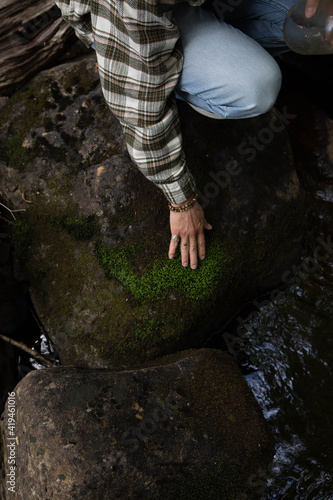 Fototapeta Naklejka Na Ścianę i Meble -  Cropped man crouching on rock by river