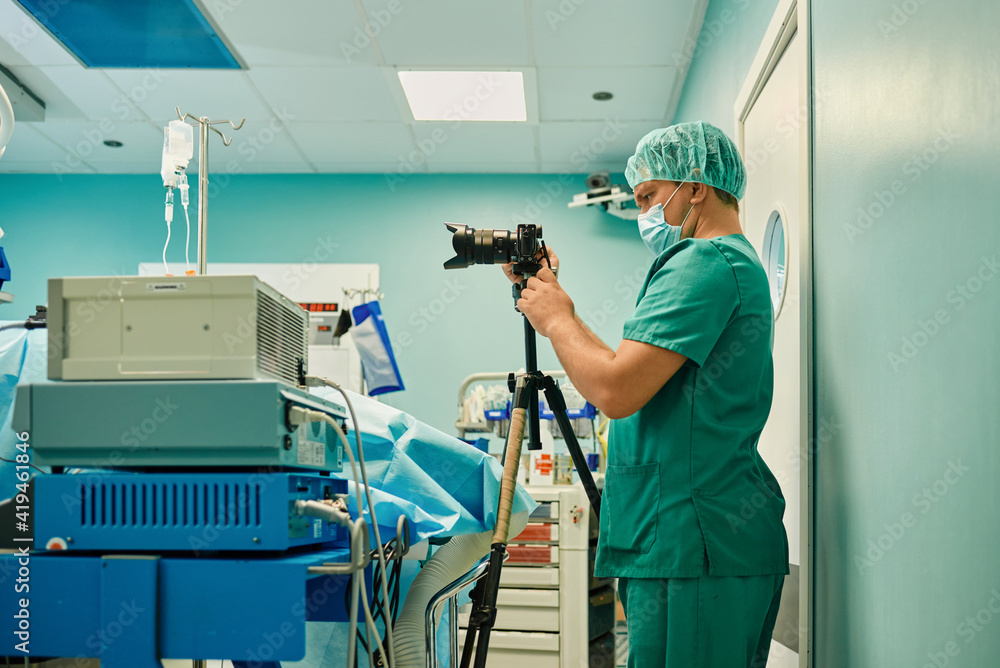 Side view of unrecognizable young male medical photographer in sterile ...