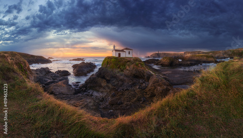 Spectacular landscape of island of Pancha with small house against cloudy sundown sky in Ribadeo in Spain photo